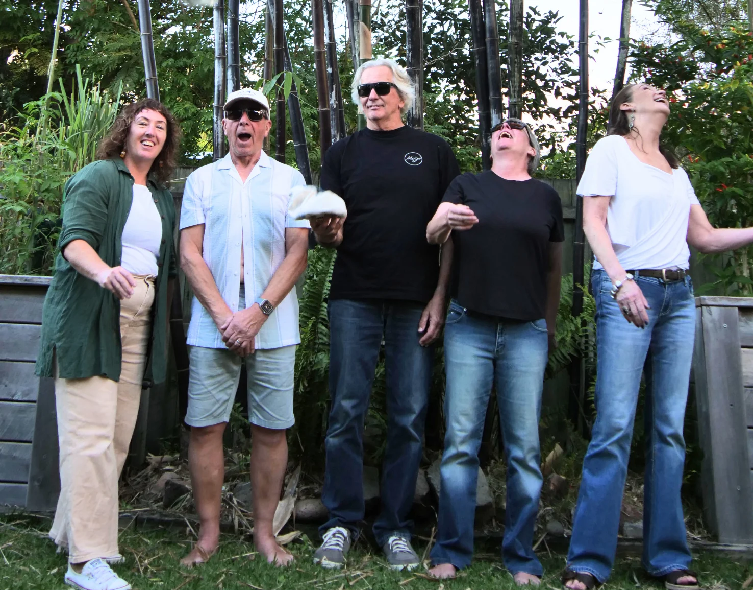 The band laughing together in a garden